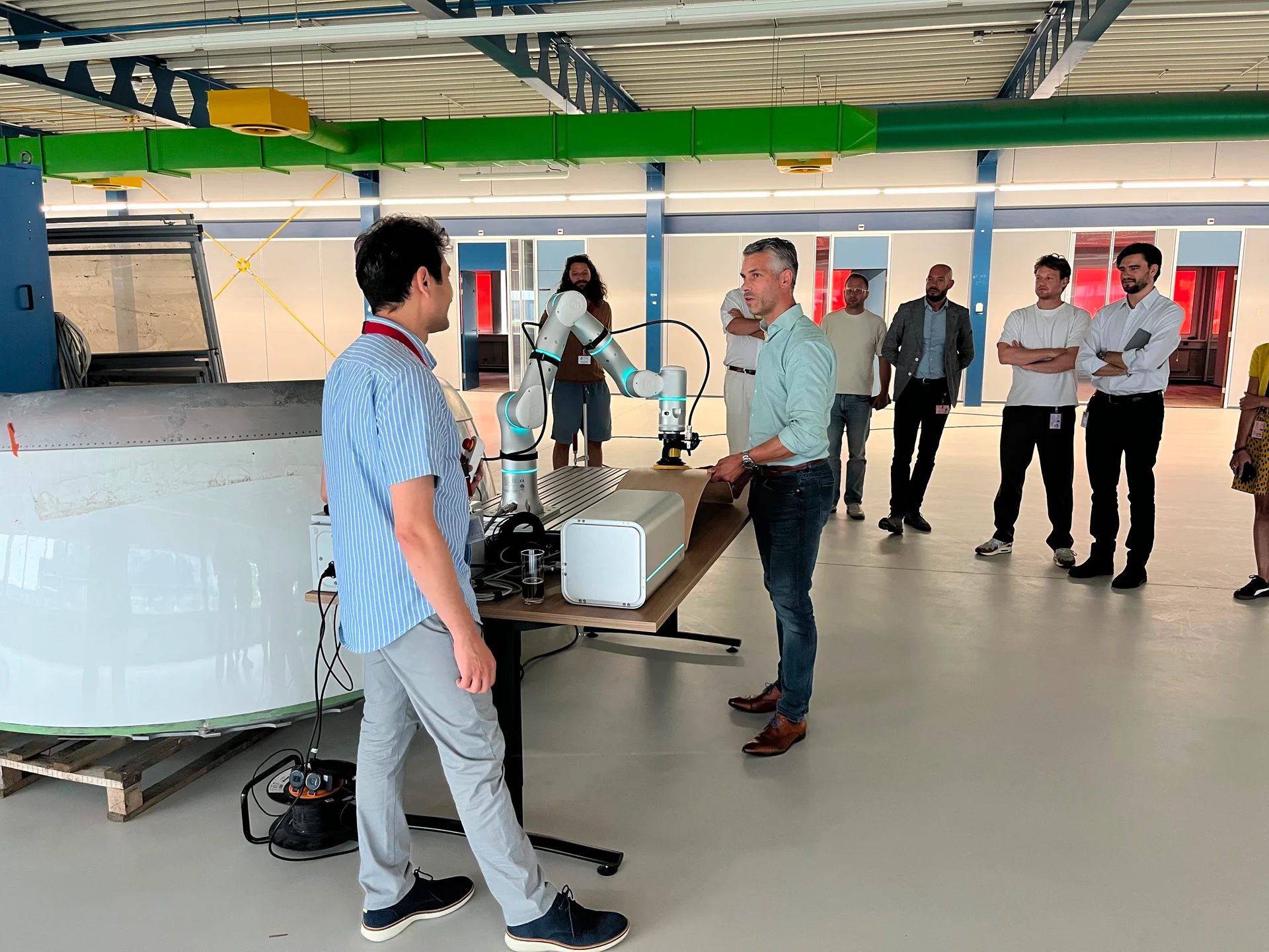 Participants observing the Robita finishing robot with a hand-positioned sample at Hive Aerospace.